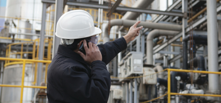 An ExxonMobil engineer points at refinery while on a phone call.