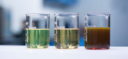 Three lubricants varying in opacity in beakers side-by-side in a laboratory.