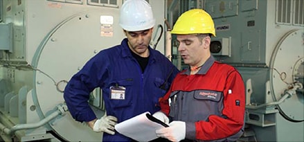 Workers reading documents in engine room