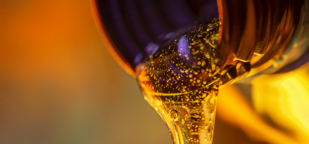 Liquid stream of oil flows from the neck of the bottle close-up