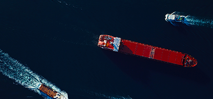 Marine traffic of a busy harbour from above. Nautical vessels cruising different directions at the port.