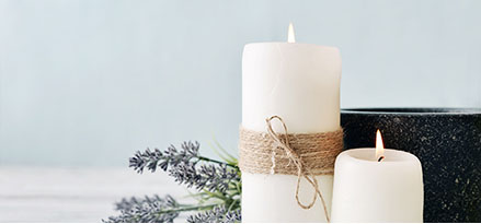 White pillar candles on table with lavendar sprigs behind