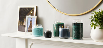 colorful candles in glass jars on fireplace mantle