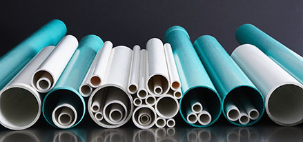 blue and white pvc pipes laying in a pile on a reflective surface with dark background