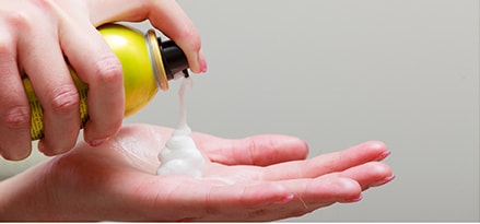 Female adding hair mousse to hand