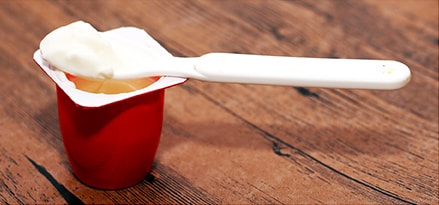 Red yogurt cup with white plastic spoon