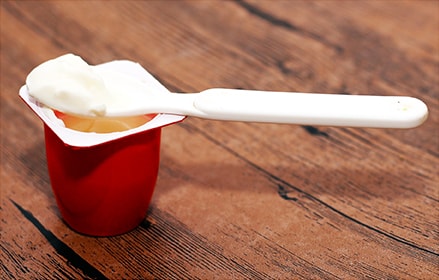 Red yogurt cup with white plastic spoon